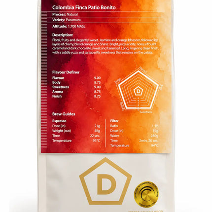 A bag of Danes Coffee Roastery Colombia Finca Patio Bonito espresso on a clean white background. The packaging features a red and orange gradient label with product details, a gold hexagonal logo, and a gold seal.