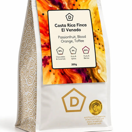 Angled view of Costa Rica Finca El Venado single origin coffee beans in Danes Coffee Roasters' 200g bag, showing the colourful front label and patterned side.