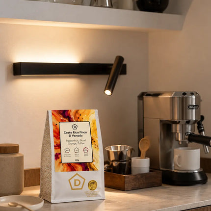 Danes Costa Rica Finca El Venado single origin coffee bag displayed on a modern kitchen counter beside a home espresso machine.