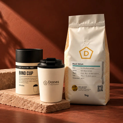 Danes Black Velvet coffee and branded Fressko reusable cup displayed against a warm terracotta background.